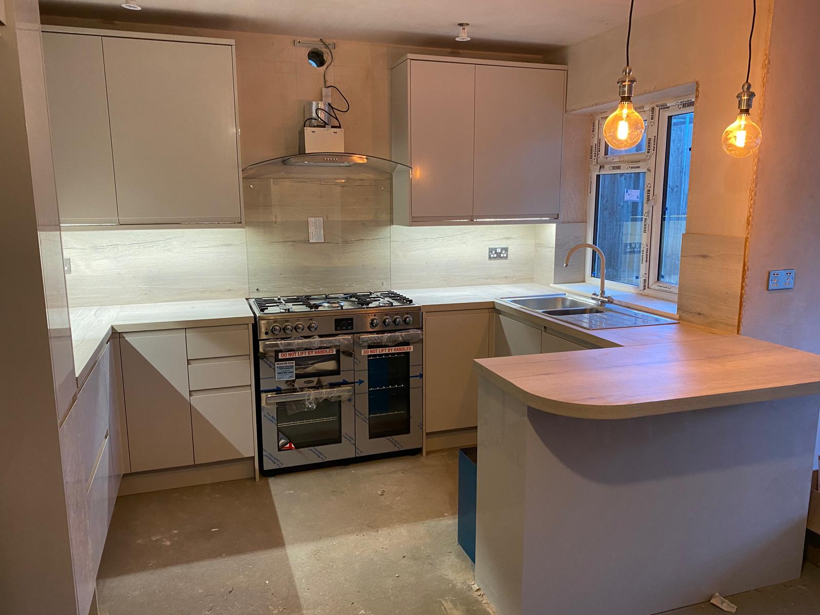 Cream gloss kitchen with range cooker, oak worktop and pendant lighting during fit-out by DBD Builders Ltd