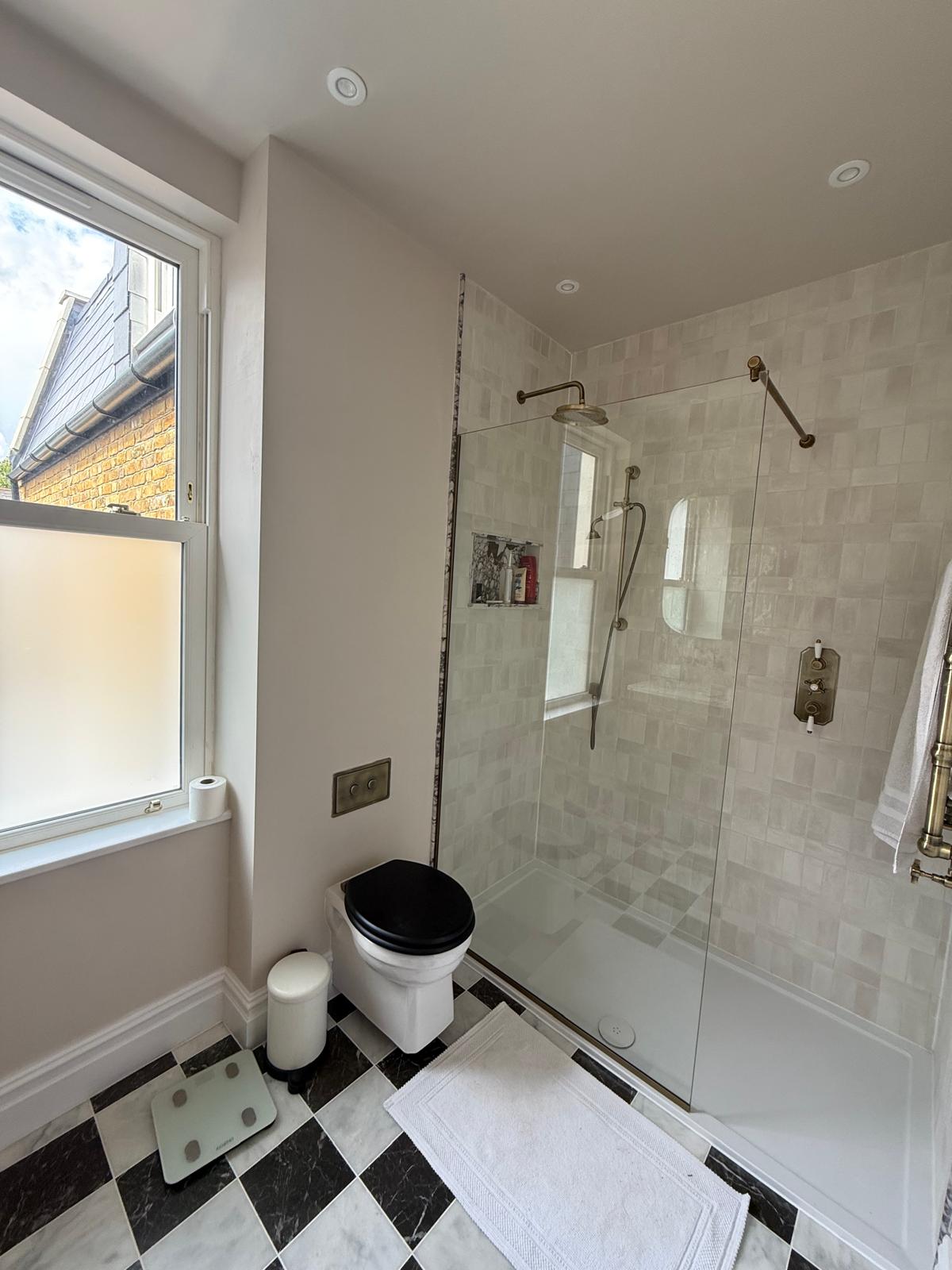 Finished bathroom with chequerboard floor tiling and glazed shower enclosure by DBD Builders Ltd