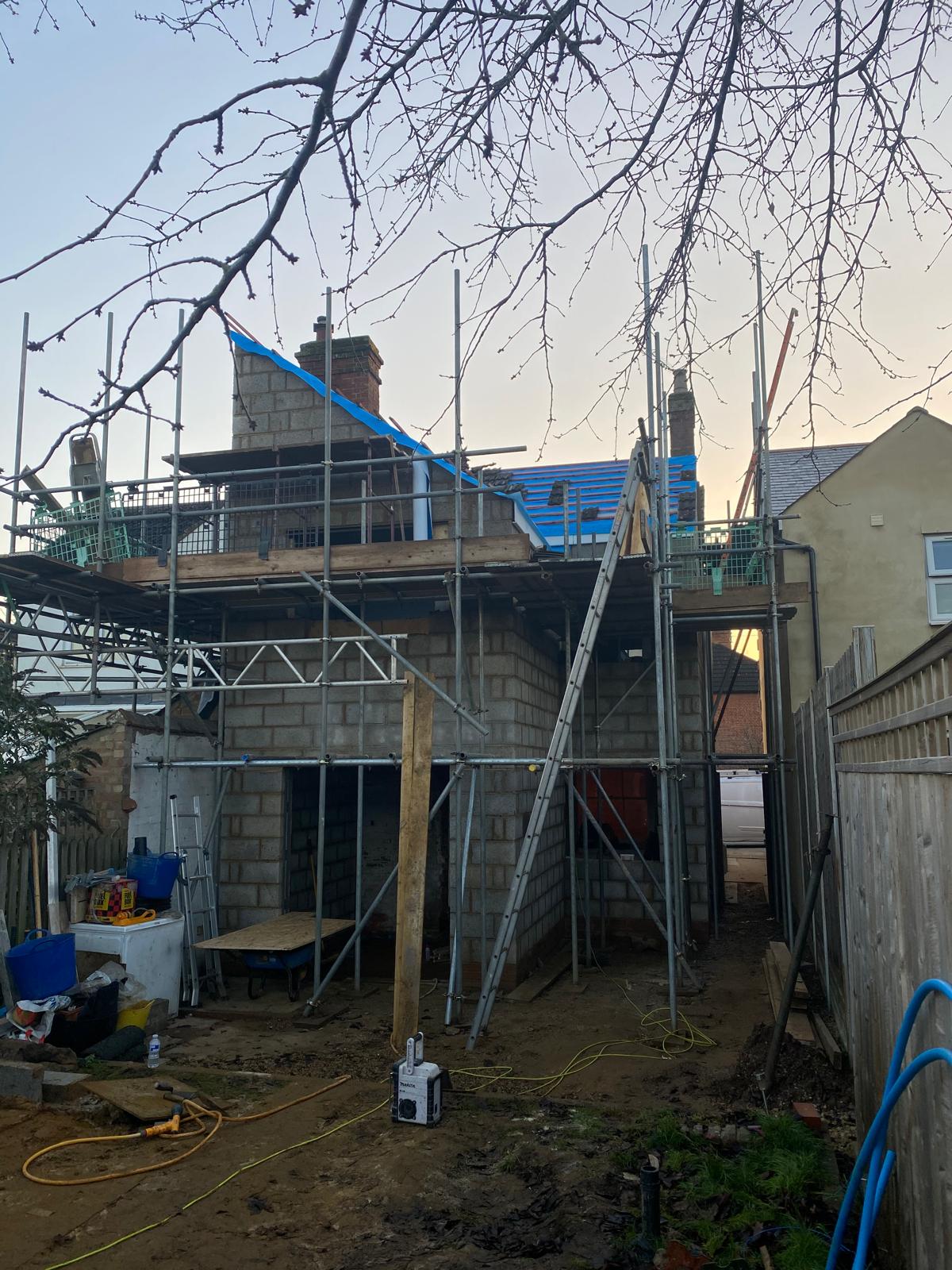 Scaffolded two-storey rear extension in blockwork with roof timbers going on by DBD Builders Ltd