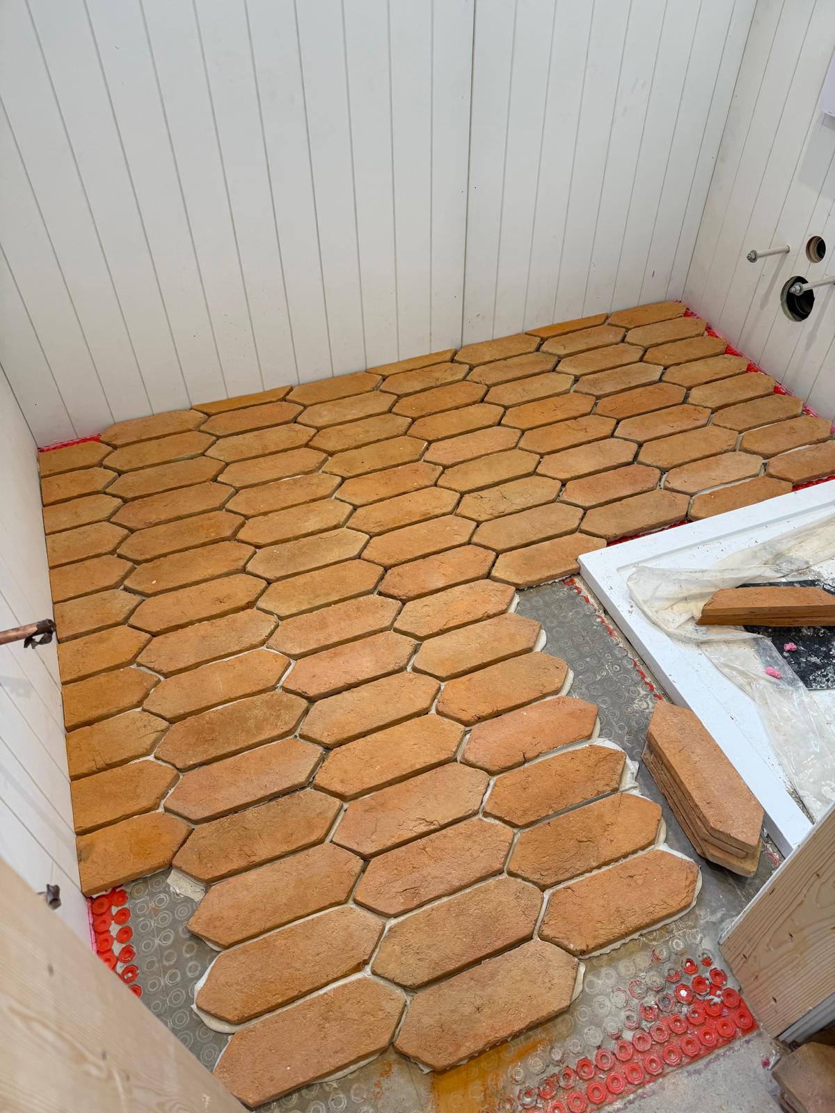 Terracotta hexagon floor tiling part laid in a panelled cloakroom by DBD Builders Ltd