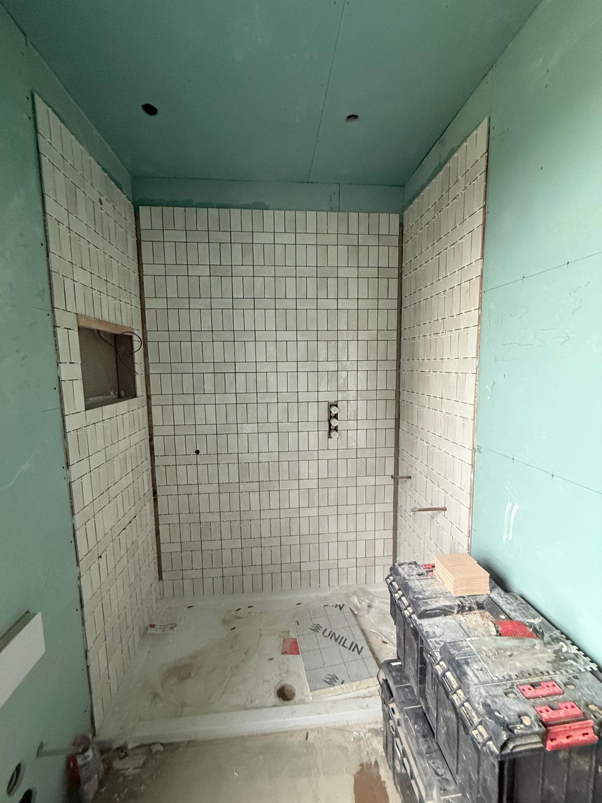 Tanked shower boards with white tiling being applied by DBD Builders Ltd