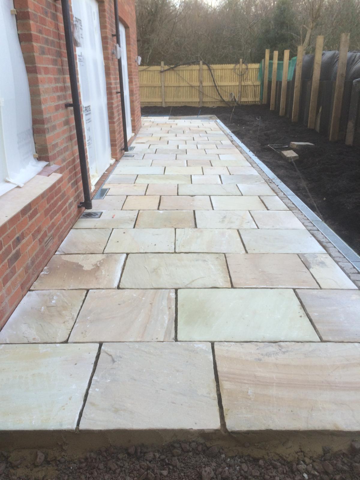 Indian sandstone paving laid alongside a new build with channel drainage by DBD Builders Ltd